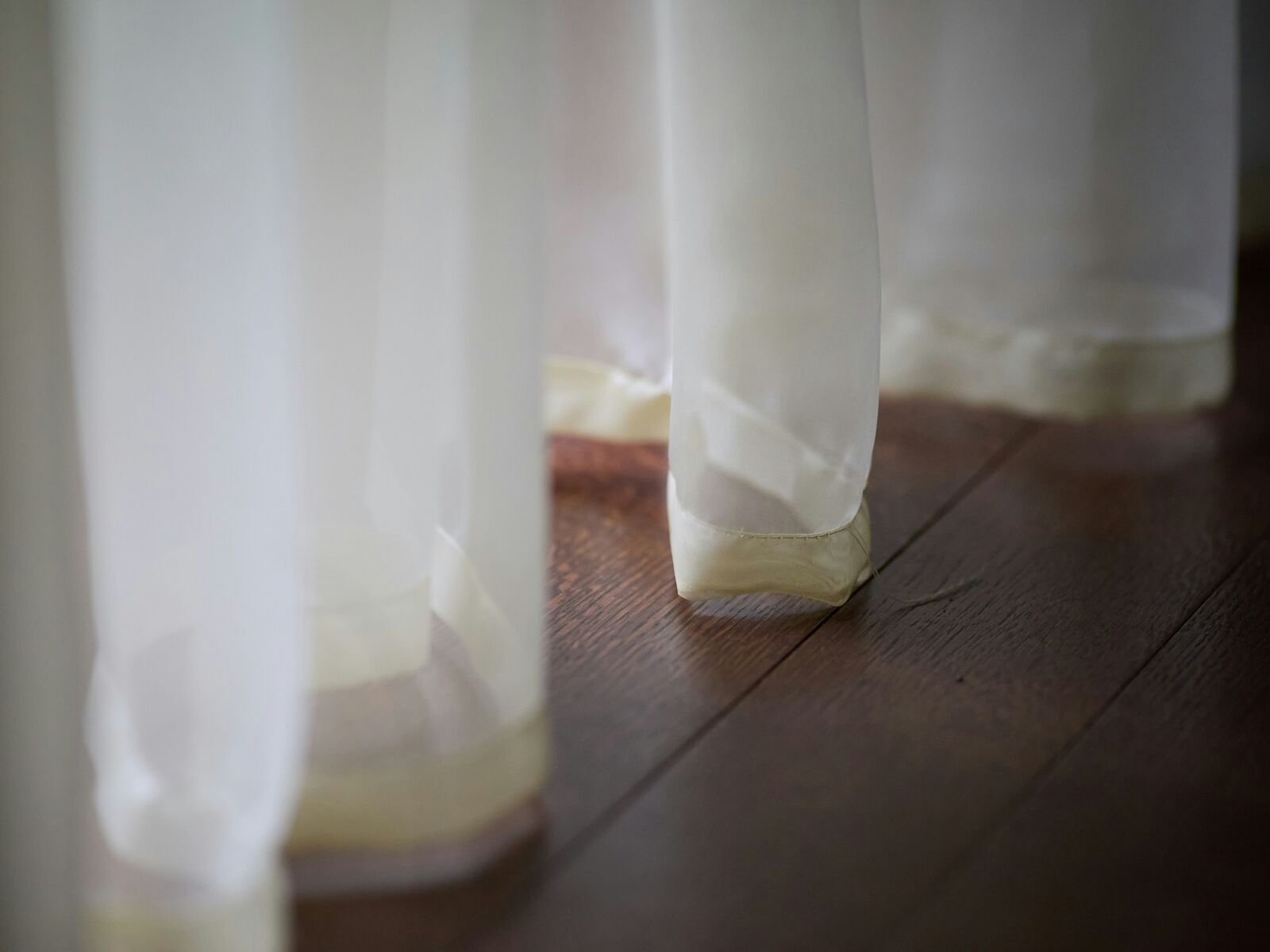 Visillos blancos translúcidos sobre suelo de madera